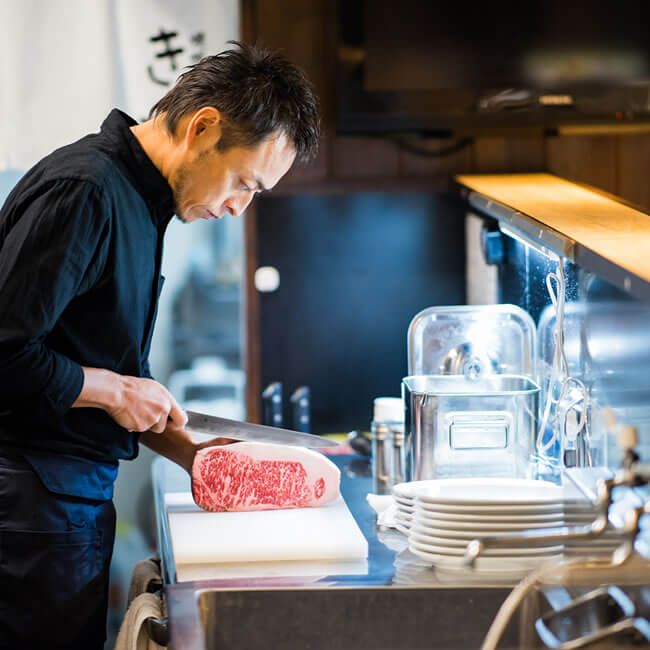 肉をカットする焼肉きっず店主